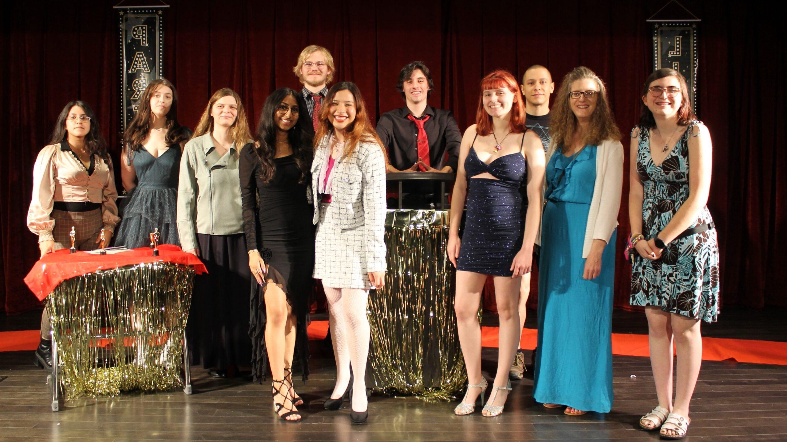 10 students and their instructor on stage in theatre